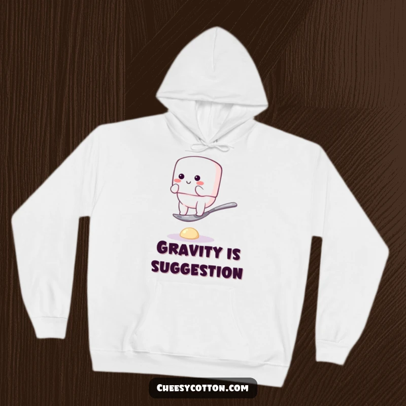 Funny hoodie featuring a fluffy marshmallow character hilariously attempting to balance on a tiny spoon, offering warmth and humorous visual delight.